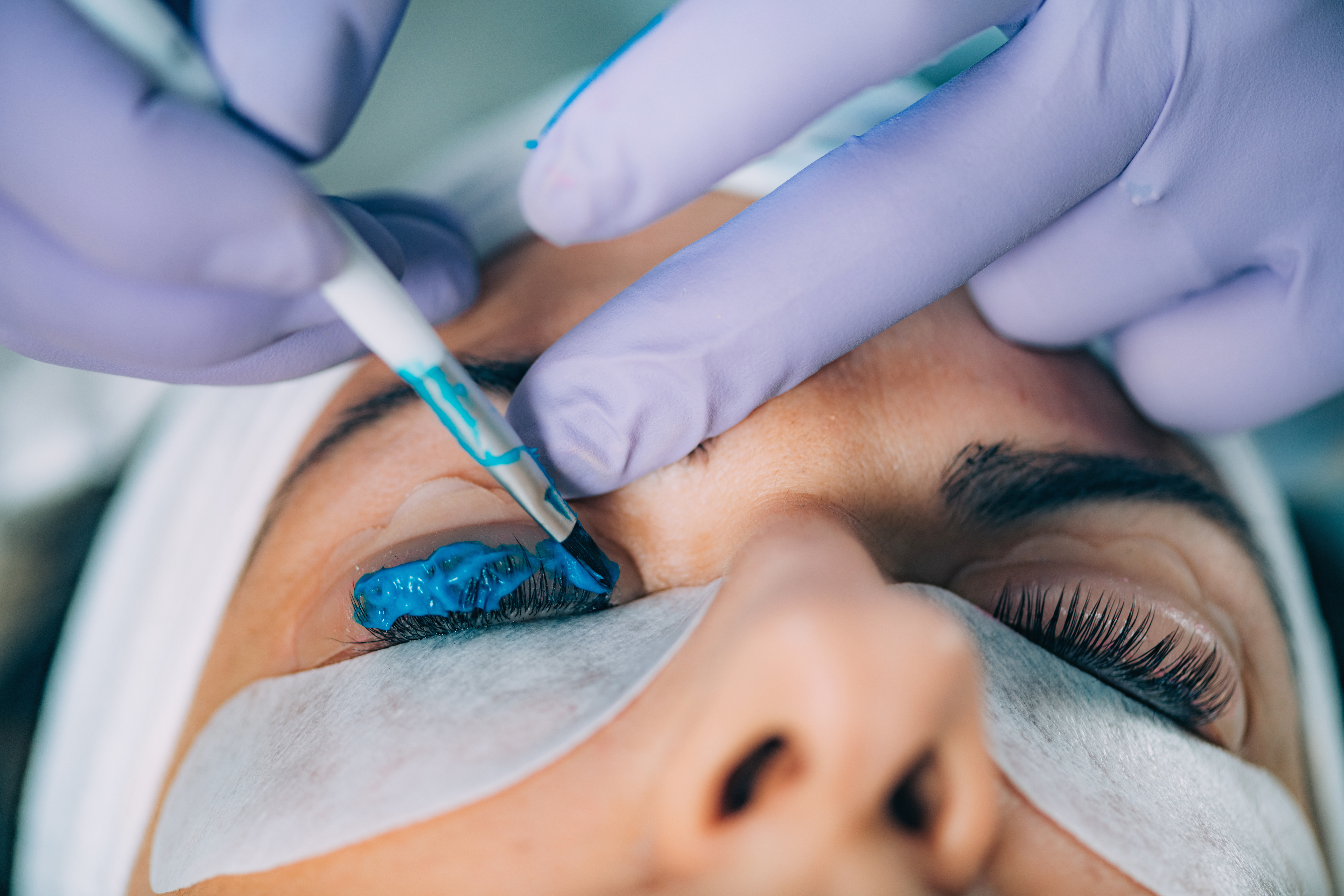 Cosmetologist Puts BluePaint on the Eyelashes During Lash Lifting Procedure. Laminating Eyelashes.