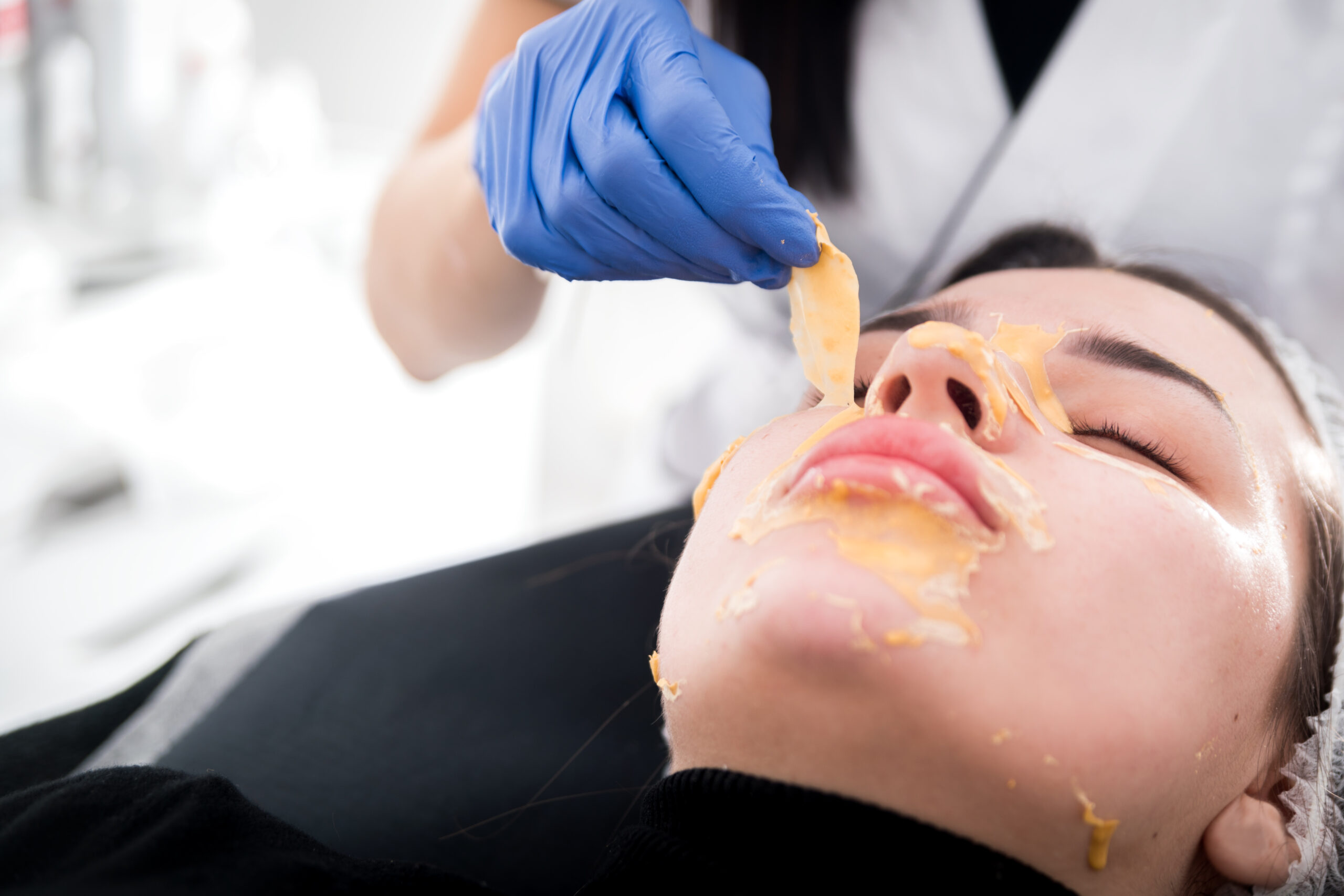 Beautician removing facial mask at cosmetic clinic, cosmetology treatment skincare face